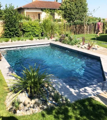 Piscine et plage en pierre dans un jardin paysager