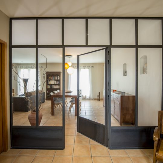 salon avec grande verriere design avec porte battante en acier
